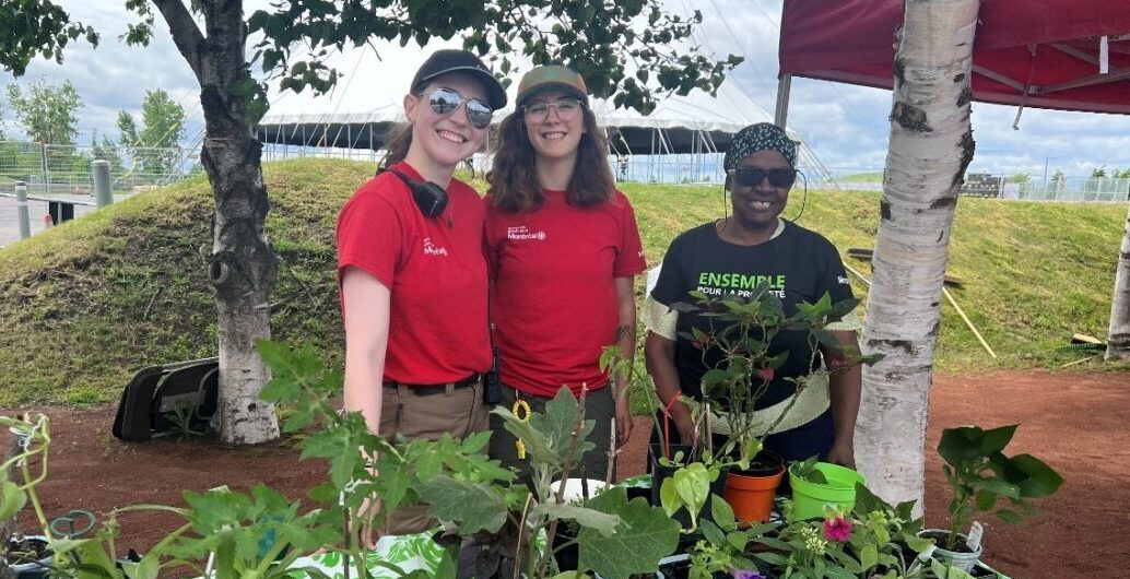 Three women standing in front of a plants stall