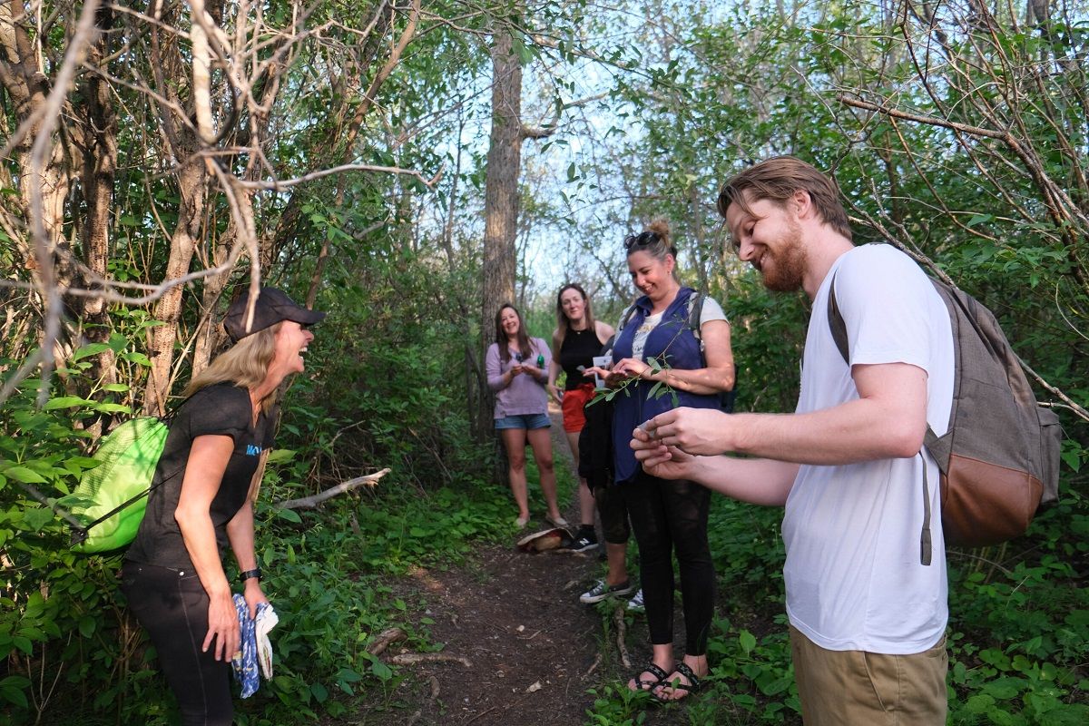People holding small plants and laughing during a walking tour in a forest