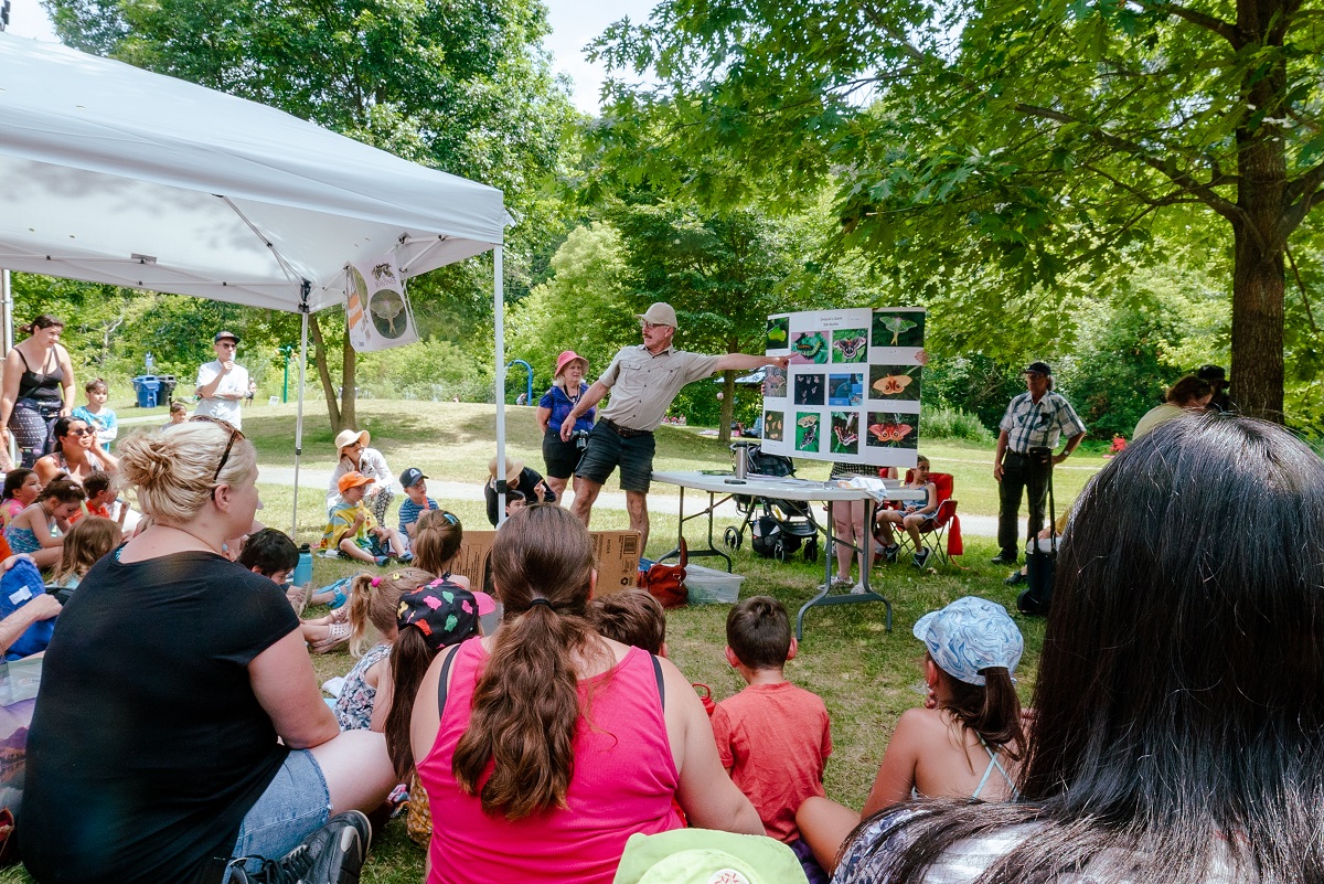 A man showig photos of caterpillars and butterflies to a group of kids